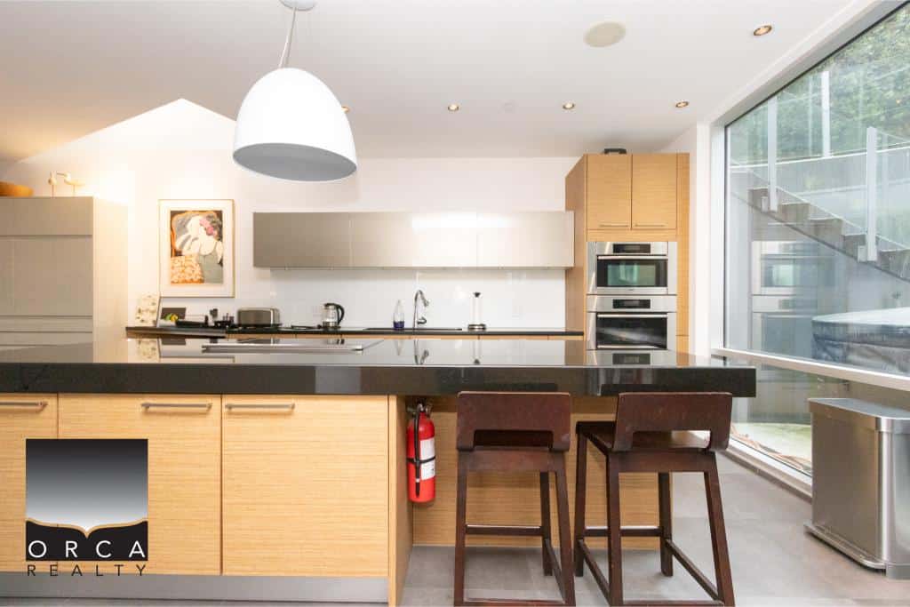 Bright and contemporary kitchen featuring sleek cabinetry, stainless steel appliances, and large windows providing ample natural light at Ansell Place. Perfect for modern living and entertaining.