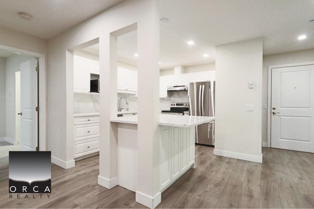 Spacious and bright kitchen featuring white cabinets, stainless steel appliances, and open layout, perfect for family living and entertaining in Surrey.