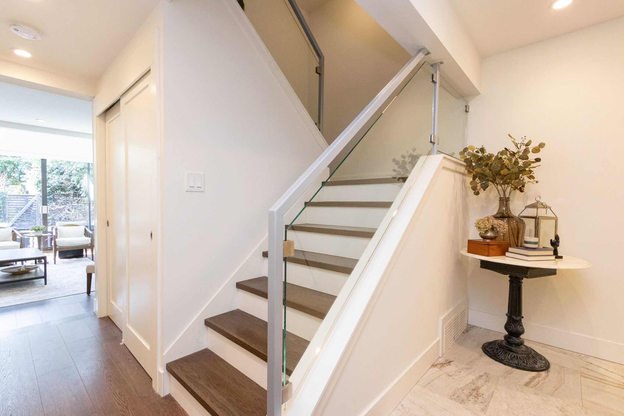 Modern West Vancouver Home Interior Bright and airy staircase area in a West Vancouver home, featuring contemporary design with white walls, wooden stairs, and elegant decor accents.