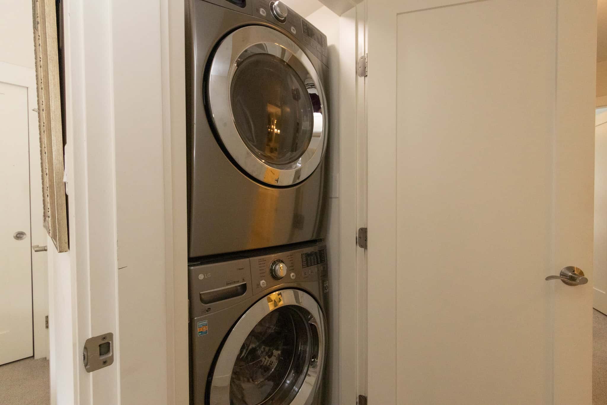 Modern laundry area with stacked washer and dryer units in a residential home. Efficient laundry space featuring a sleek, stacked washer and dryer in a bright, clean utility closet.