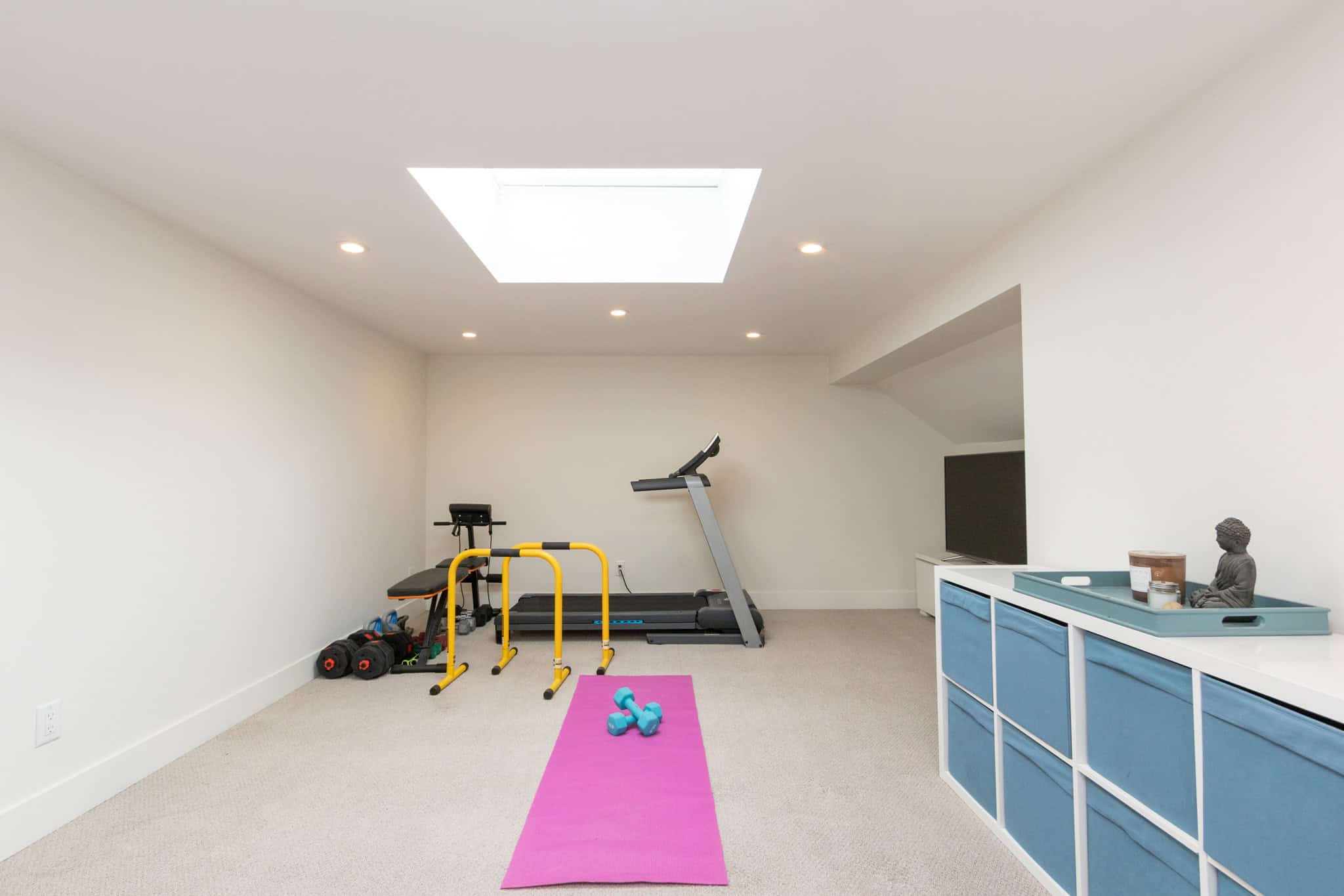 Modern West Vancouver home gym interior with fitness equipment and bright natural lighting. Home gym in West Vancouver with treadmill, weights, and workout accessories for active living.