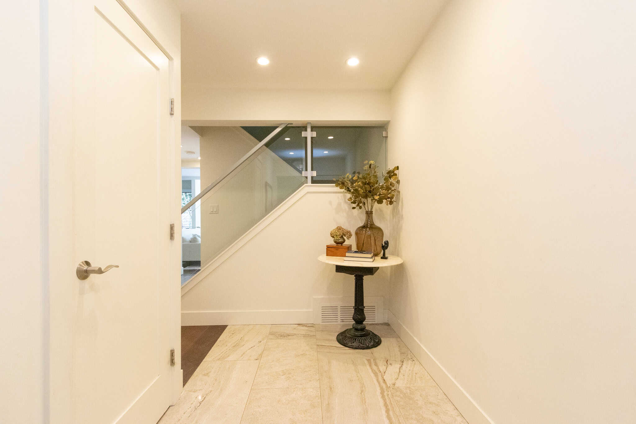 Modern West Vancouver Home Interior Bright, minimalist interior of a West Vancouver home with white walls, recessed lighting, and a decorative table with a vase of flowers near the staircase.