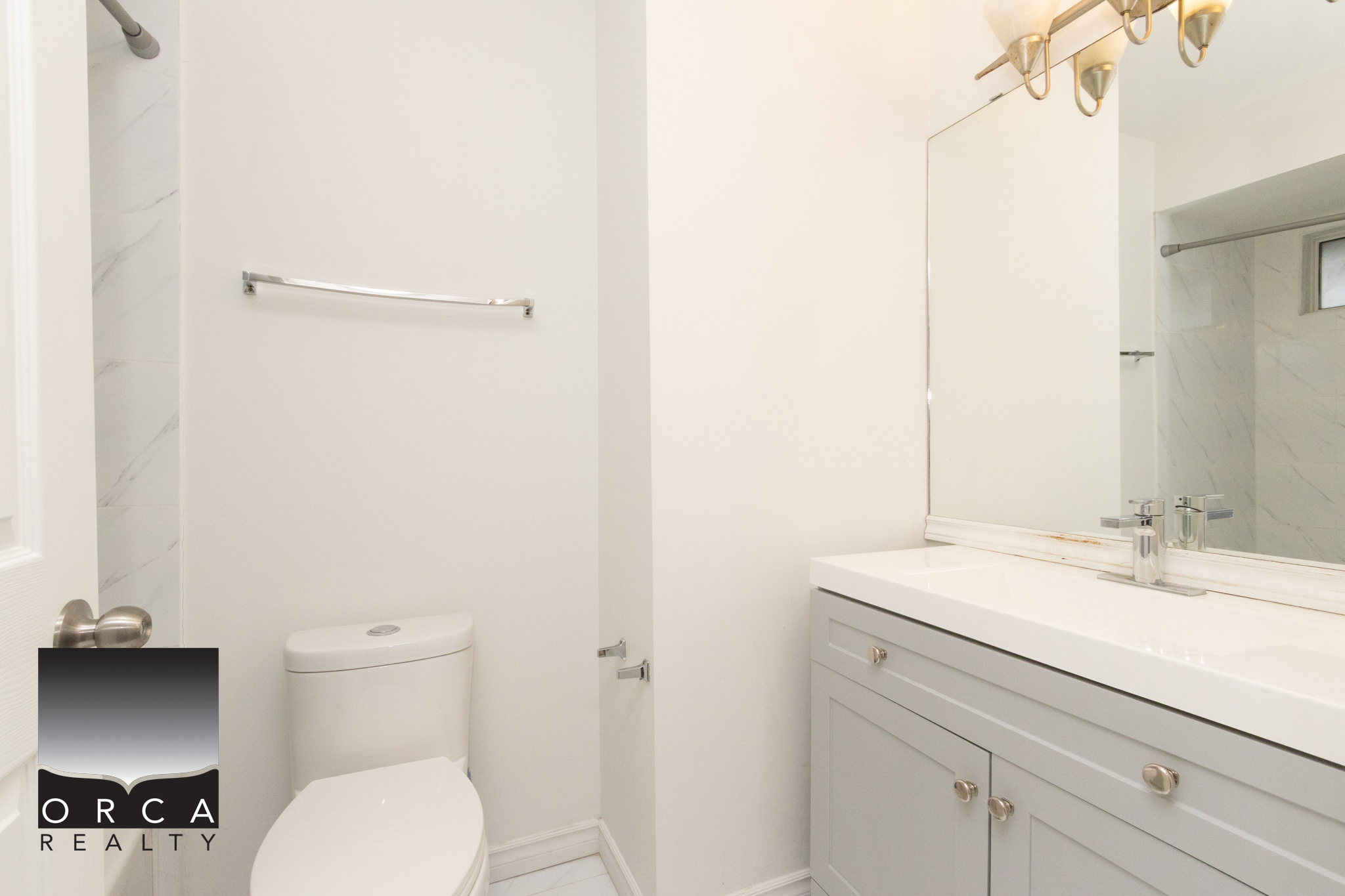 Bright and clean bathroom featuring a white toilet and vanity with a large mirror, perfect for a comfortable home in Richmond.