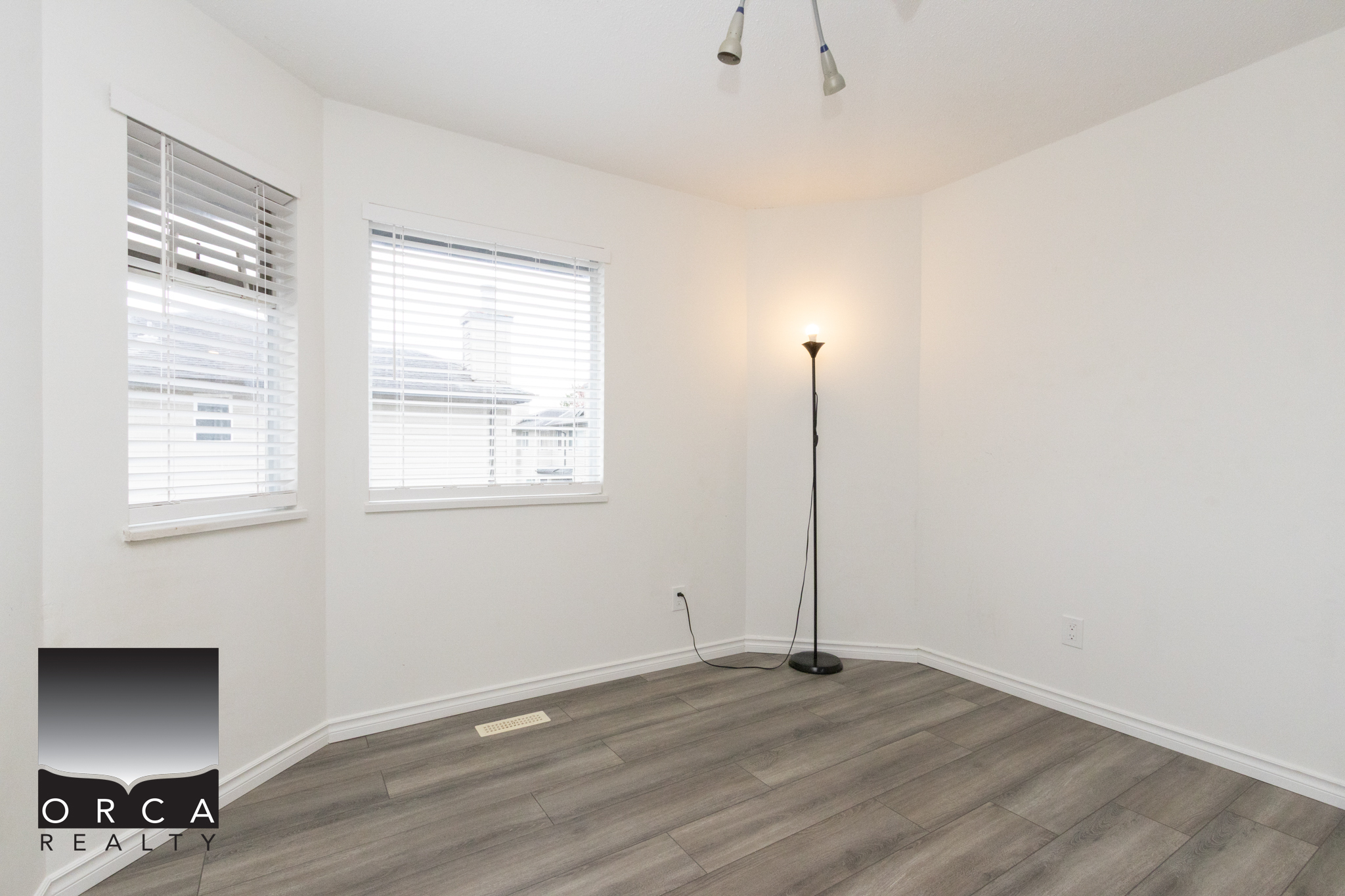 Bright empty room with large windows and hardwood flooring in Richmond property.