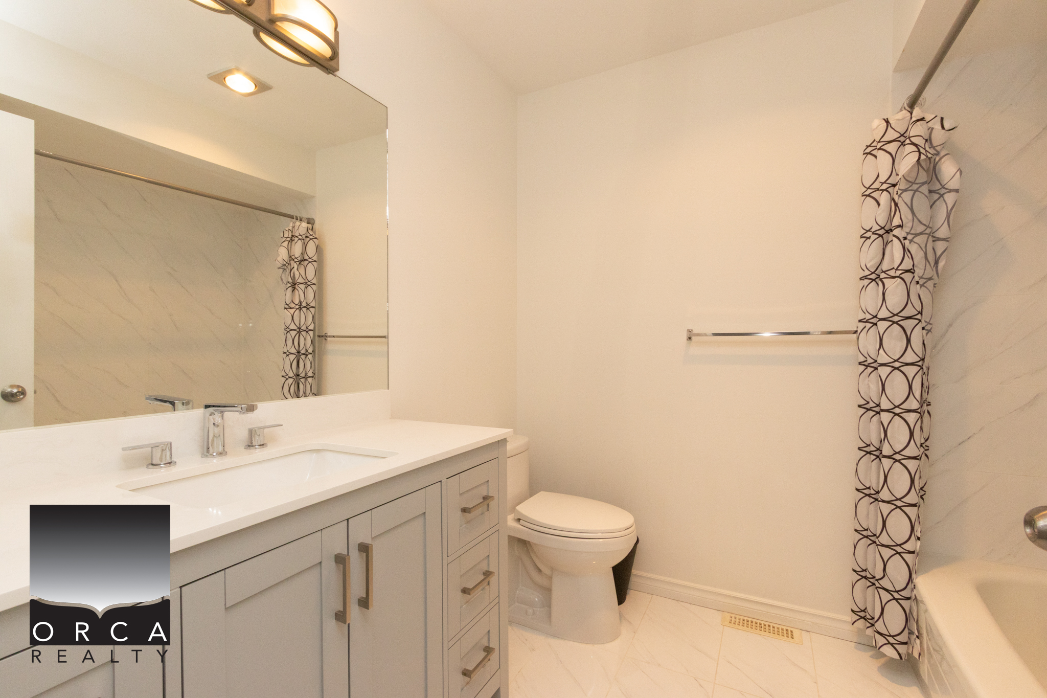 Bright bathroom featuring a white vanity with storage, a standard toilet, and a shower with a patterned curtain, located at 11-8751 Bennett Road, Richmond.
