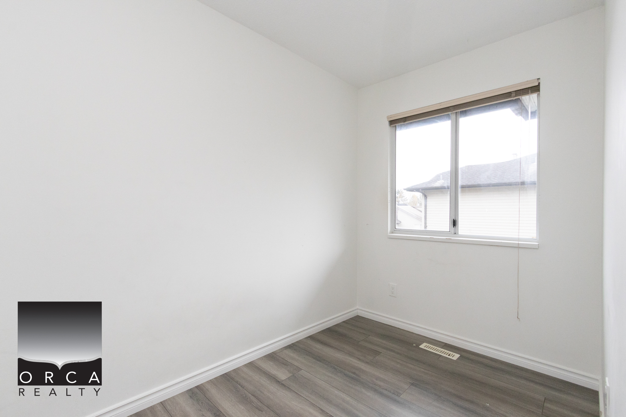 Bright empty bedroom with white walls and large window in Richmond property.