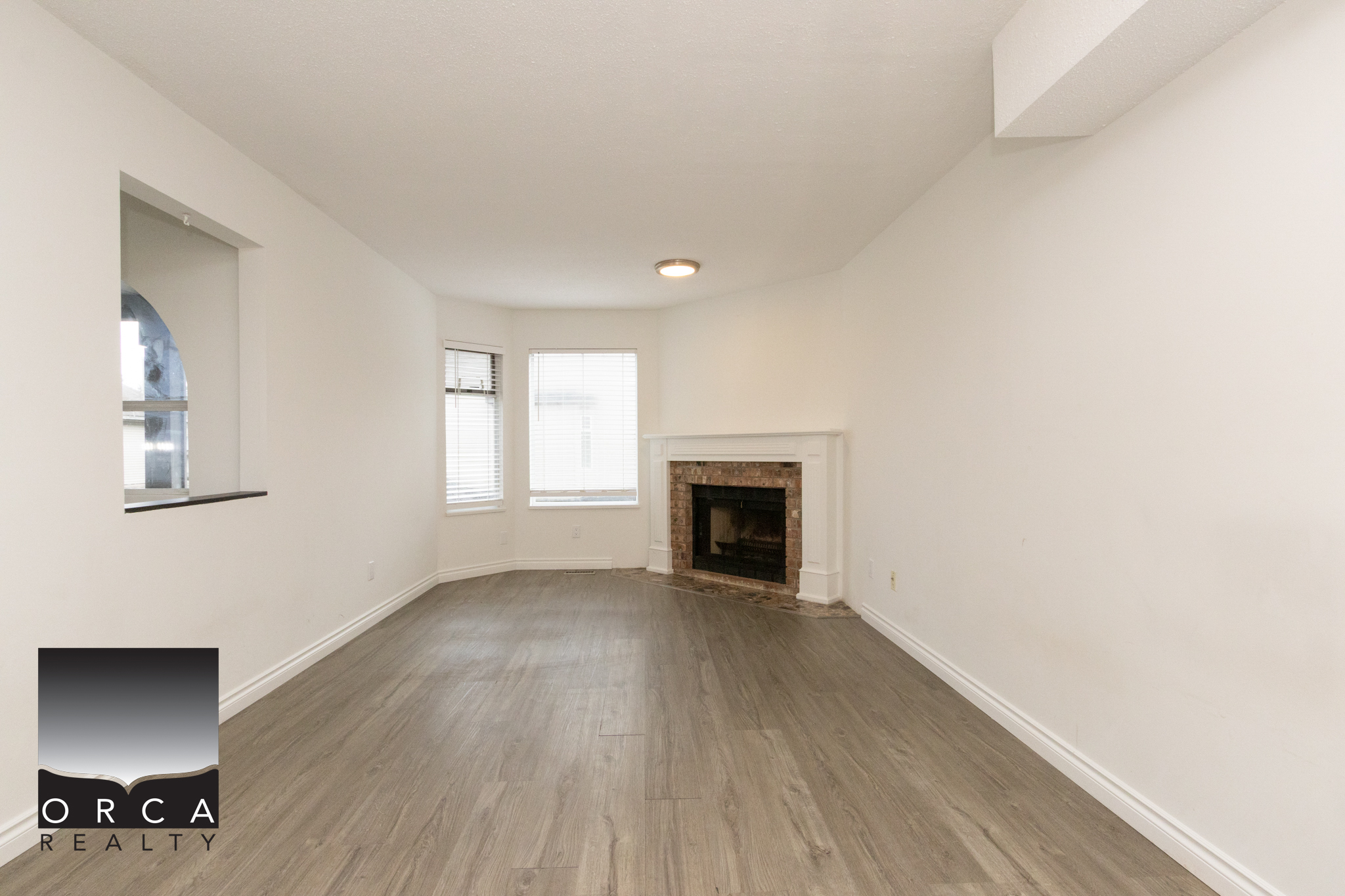 Spacious living room featuring a cozy fireplace, large windows, and neutral decor, ideal for family gatherings and relaxation in Richmond.
