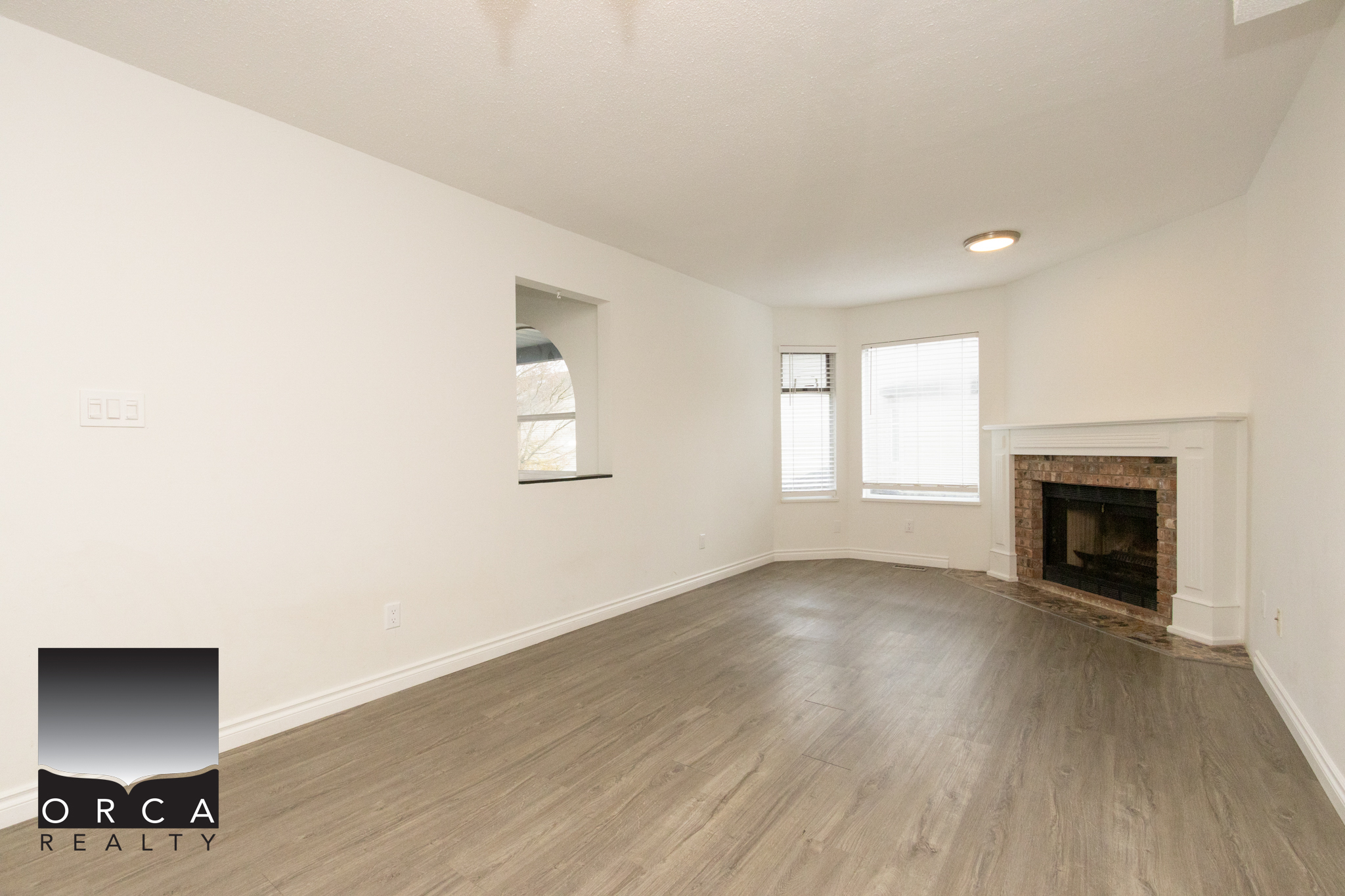Modern living room featuring a cozy fireplace and large windows in Richmond. Bright, spacious interior perfect for family gatherings and relaxation.