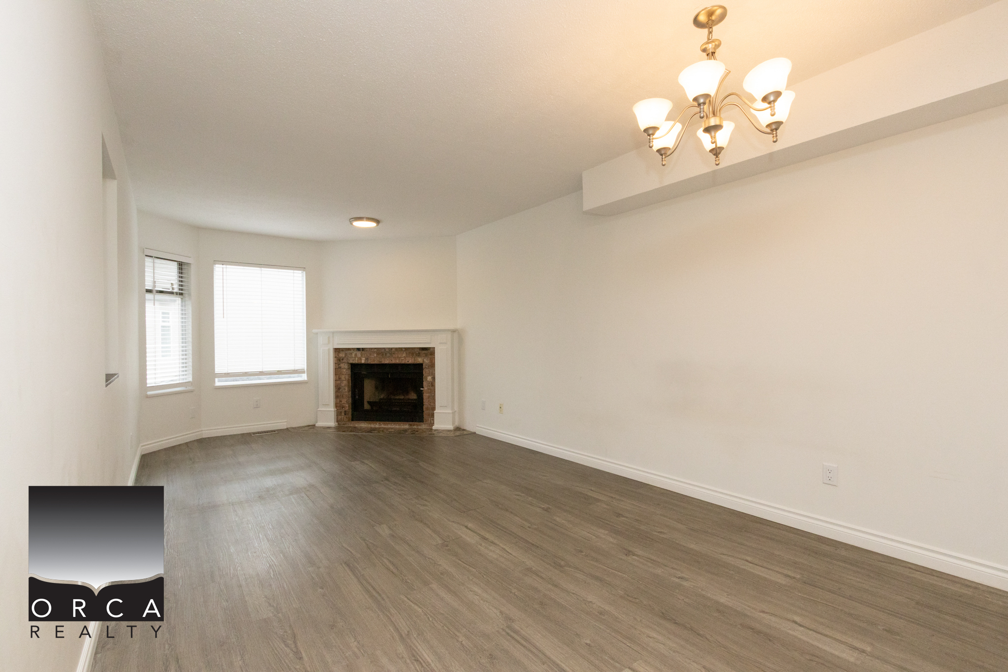 Spacious living room featuring a cozy fireplace, large windows for natural light, and neutral decor, ideal for family gatherings and relaxing in the Richmond area.