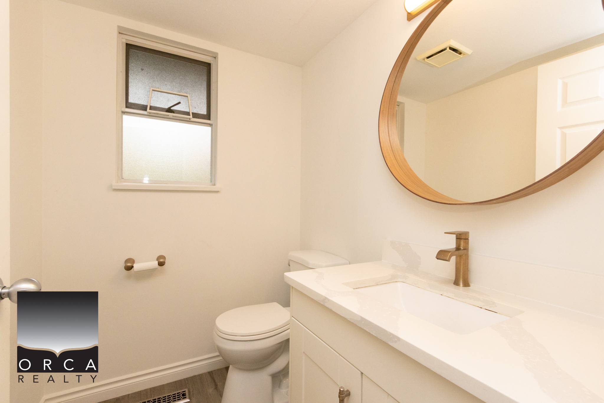 Bright and clean bathroom featuring a modern vanity, white fixtures, and a small frosted window for natural light. Perfect for a comfortable home in Richmond.