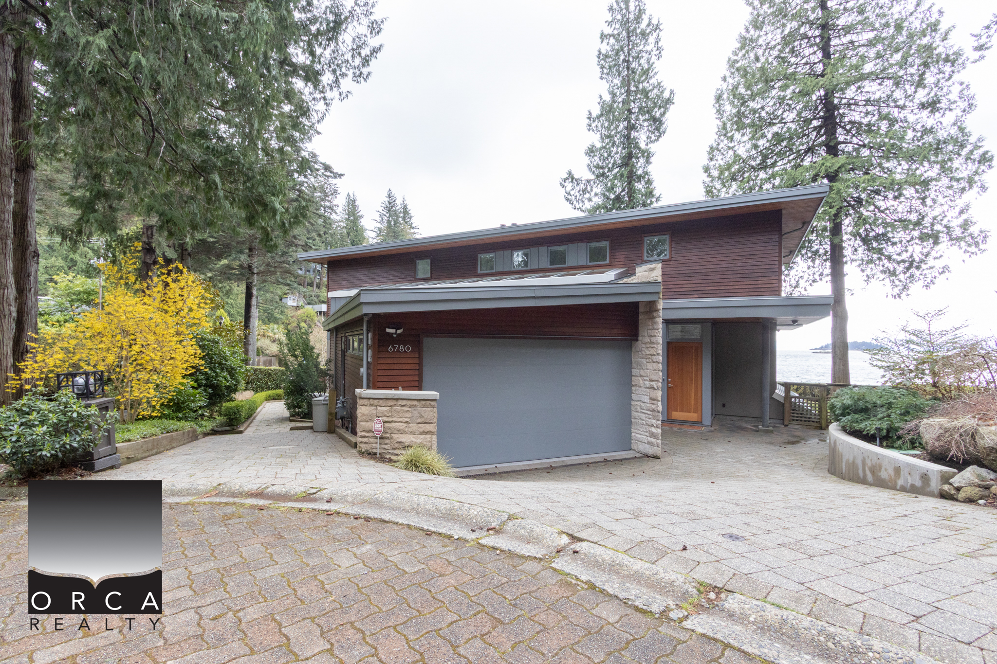 Modern West Vancouver Home with Natural Surroundings Elegant contemporary house located at 6780 Bachelor Bay Place, West Vancouver, surrounded by lush trees and landscaped gardens.