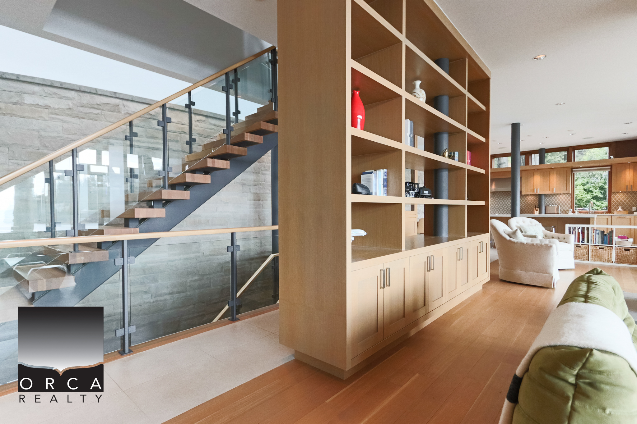 Modern interior of a West Vancouver home with a wooden staircase and built-in shelving unit. Spacious living area featuring a stylish staircase, contemporary shelving, and cozy seating, perfect for luxury West Vancouver real estate.