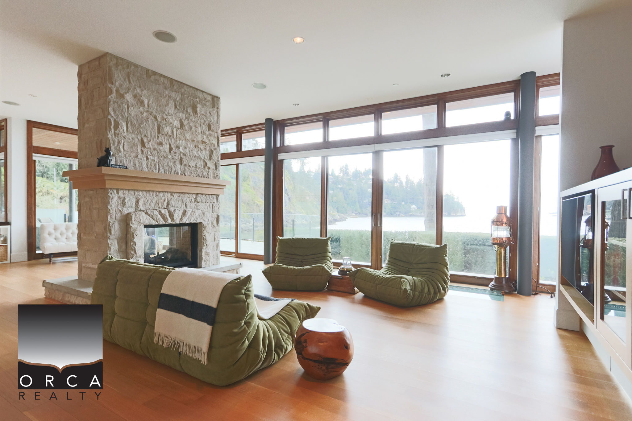 Luxury West Vancouver Living with Lake Views Spacious living room featuring large windows overlooking West Vancouver’s scenic waterfront, with modern furnishings and a cozy fireplace, perfect for relaxing or entertaining.