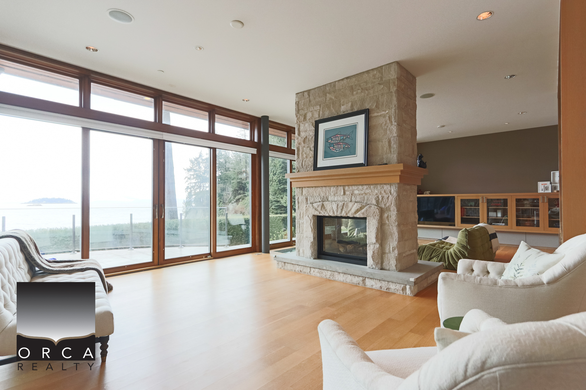 Modern West Vancouver Living Room with Fireplace and Ocean View Spacious living room in West Vancouver featuring a stone fireplace, large windows with ocean views, and contemporary furnishings, perfect for luxury home living.
