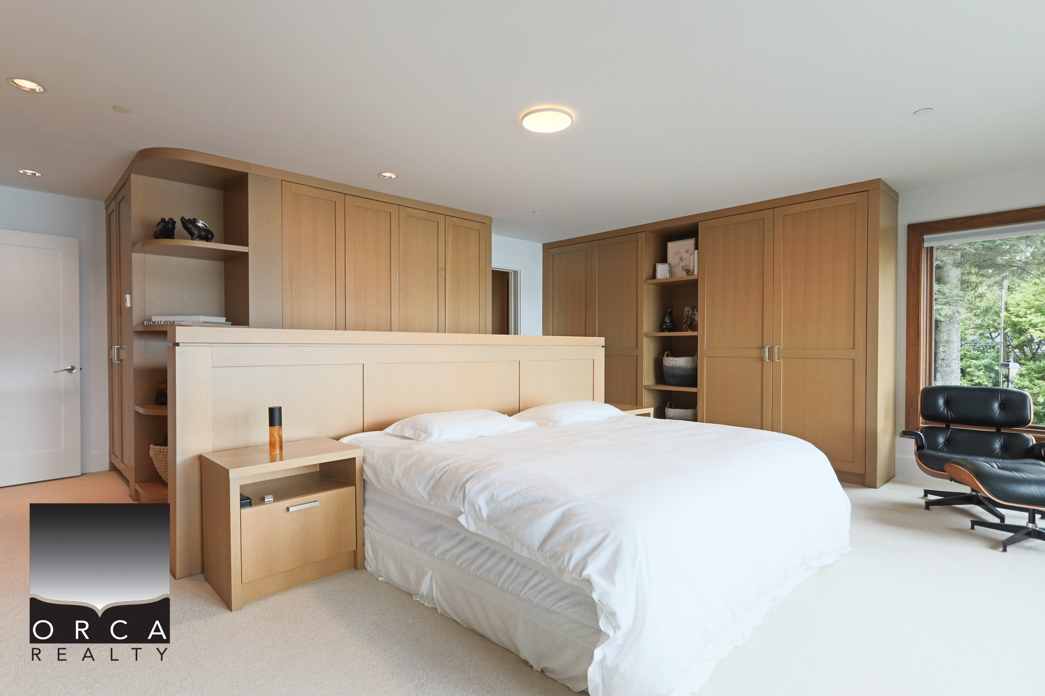 Modern West Vancouver Bedroom with Built-in Storage and Natural Light Spacious bedroom in West Vancouver with custom built-in wooden storage, large window with greenery view, and contemporary decor, ideal for luxury home living.