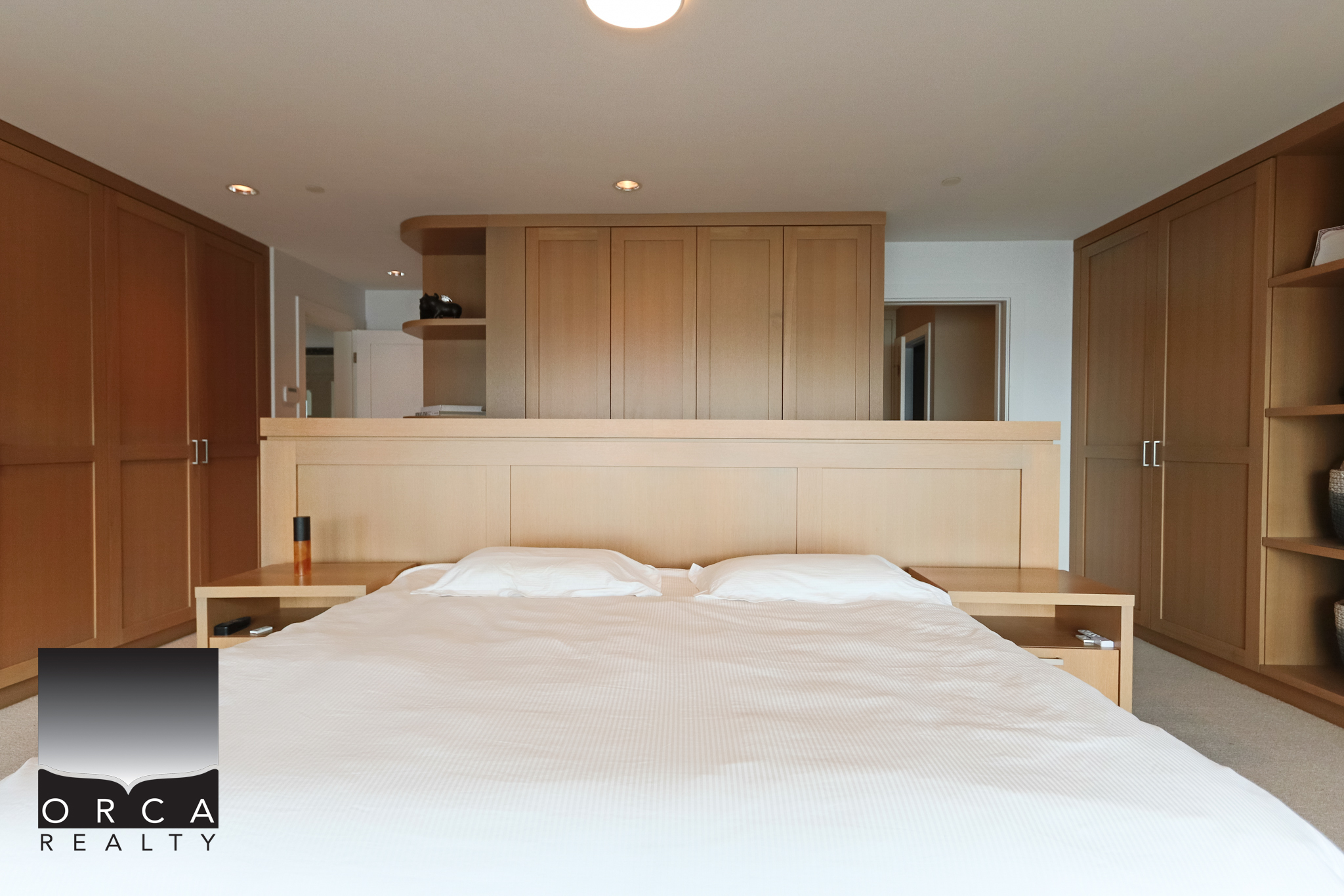 Modern bedroom with custom wood cabinetry and minimalist design. Spacious West Vancouver bedroom featuring built-in wooden closets and a cozy, clean aesthetic.