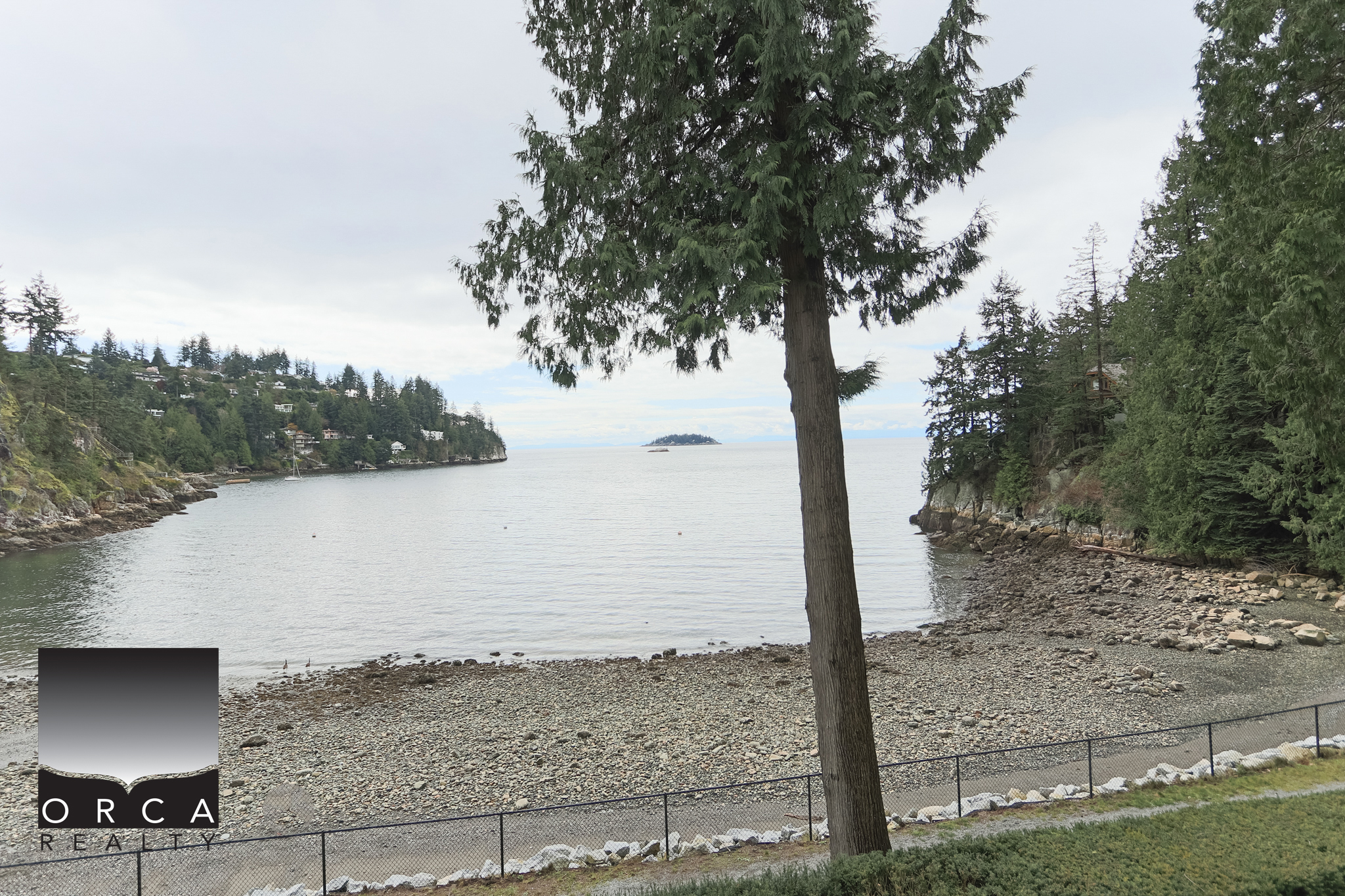 Waterfront view of Bachelor Bay Place in West Vancouver with trees and rocky shoreline. Stunning waterfront scene at Bachelor Bay Place, West Vancouver, showcasing serene waters, lush greenery, and a peaceful natural environment.