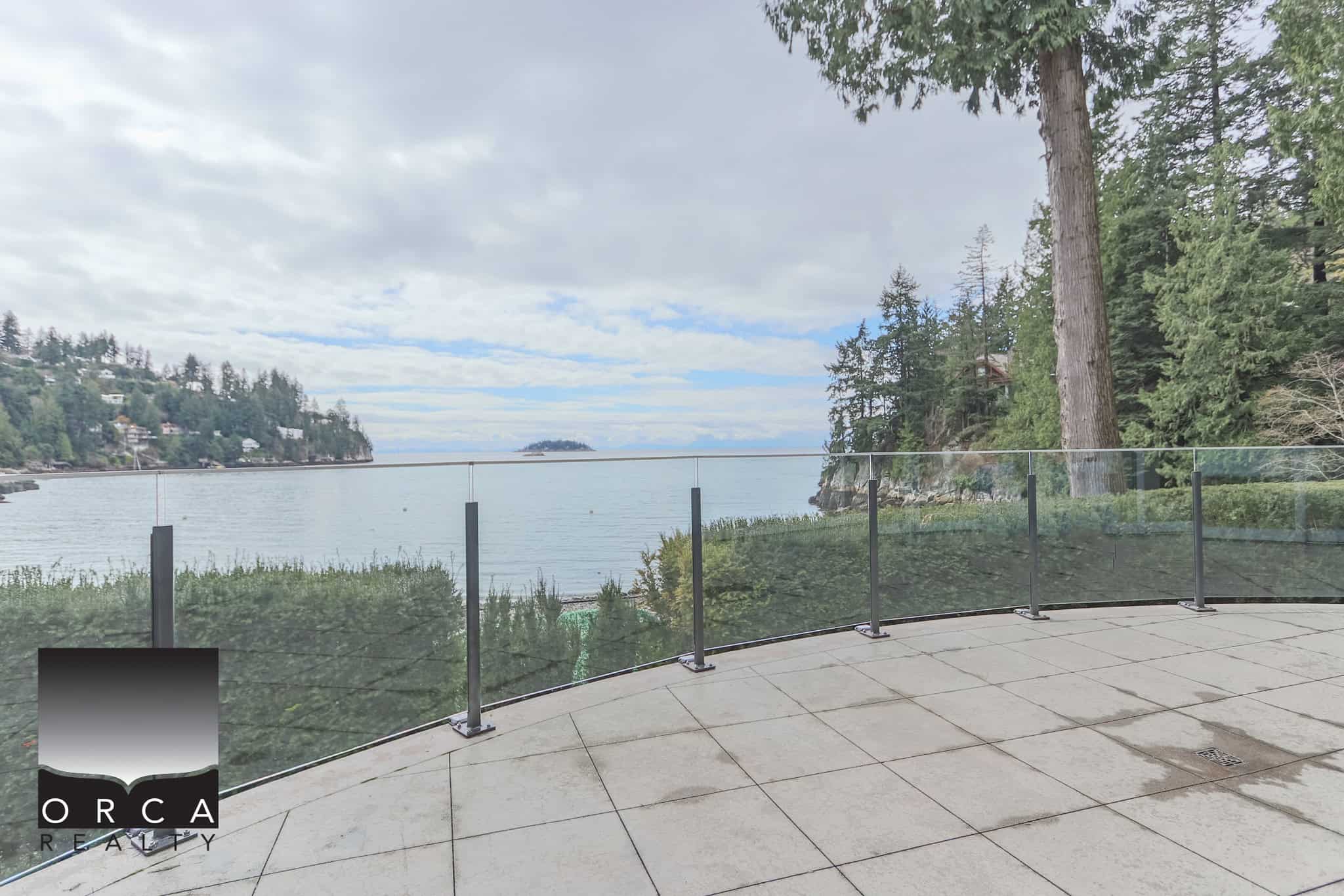 Breathtaking West Vancouver Waterfront View An expansive view of the ocean from a spacious balcony at 6780 Bachelor Bay Place, West Vancouver, showcasing lush greenery, calm waters, and a serene coastal landscape.