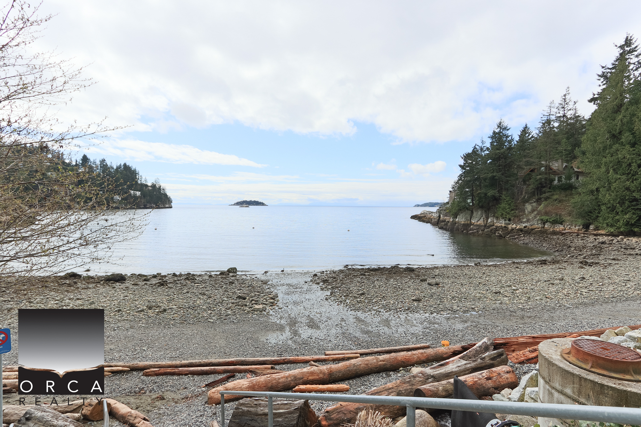 Oceanfront View at Bachelor Bay, West Vancouver Stunning waterfront scene at Bachelor Bay Place showcasing calm waters, rocky shoreline, and lush forested surroundings in West Vancouver. Perfect for real estate listings highlighting prime oceanfron.
