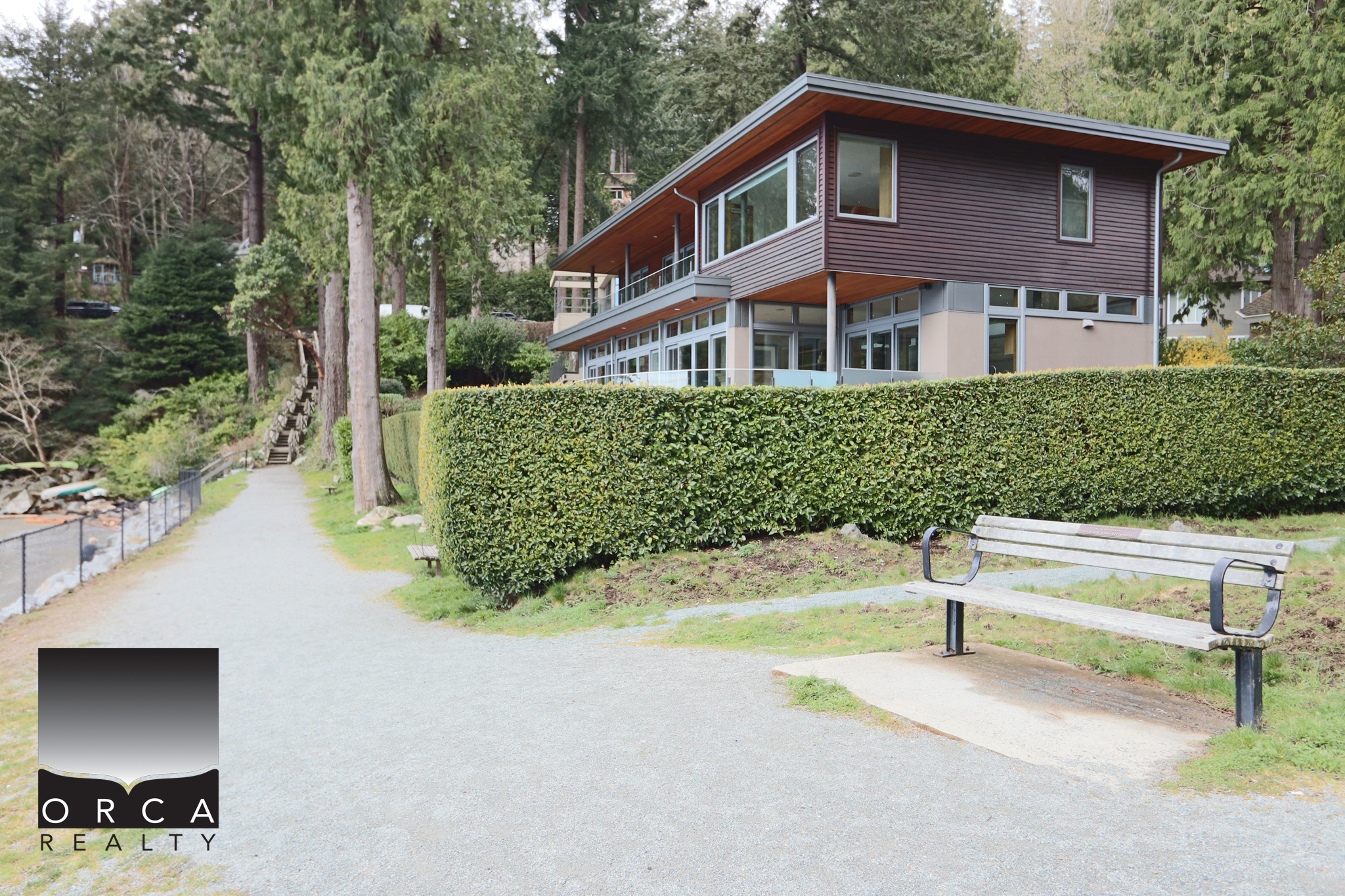 Modern West Vancouver Home with Scenic Nature Views Contemporary West Vancouver residence with large windows, surrounded by lush greenery and a well-maintained hedge, offering stunning views and outdoor relaxation space.