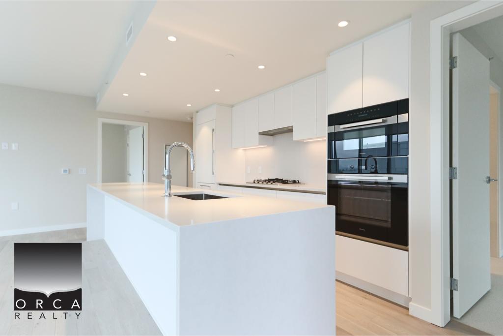 Modern white kitchen with island, sleek cabinetry, and built-in oven, perfect for contemporary home living in Victoria, BC.