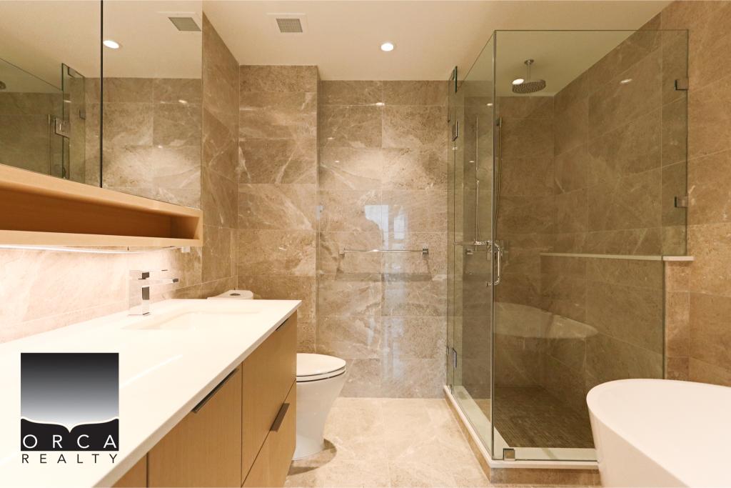 Luxurious bathroom featuring beige marble tiles, a glass shower, and contemporary fixtures, showcasing elegant design and high-end finishes in a stylish home.