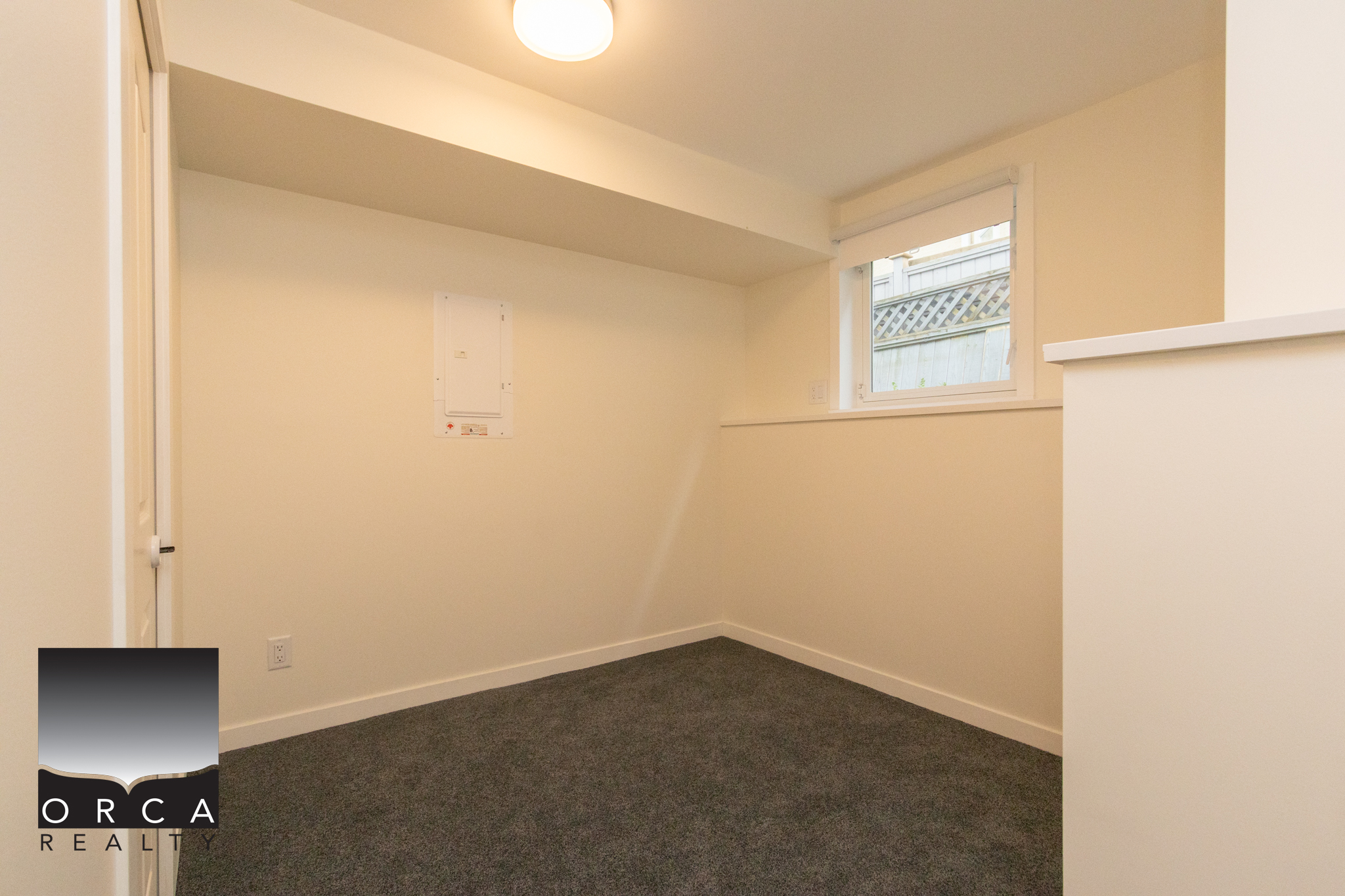 Bright empty room with white walls, a small window, and gray carpet flooring, ideal for a home office or bedroom in a residential property.