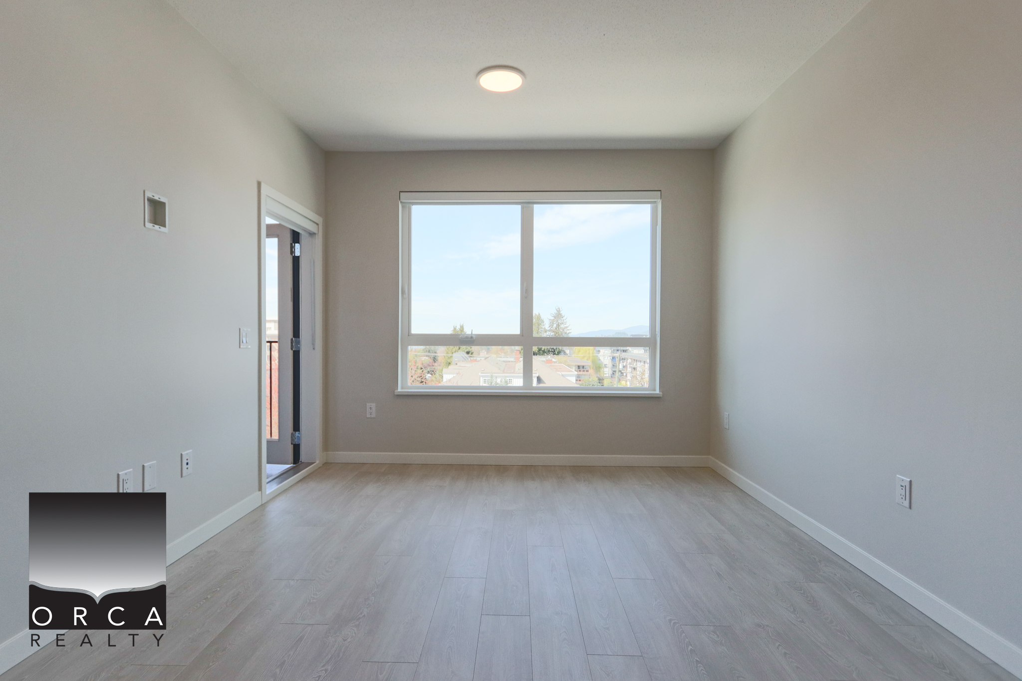 Modern Empty Living Room with Large Window Bright and spacious empty living room featuring a large window with a scenic view, white walls, and light wood flooring, ideal for new homeowners or real estate listings.