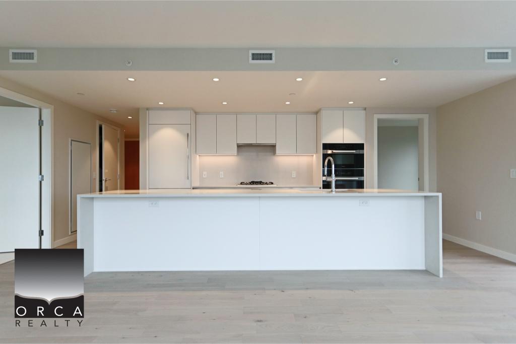 Bright, modern kitchen featuring white cabinetry, a large island, and stainless steel appliances, ideal for contemporary home living and real estate listings.