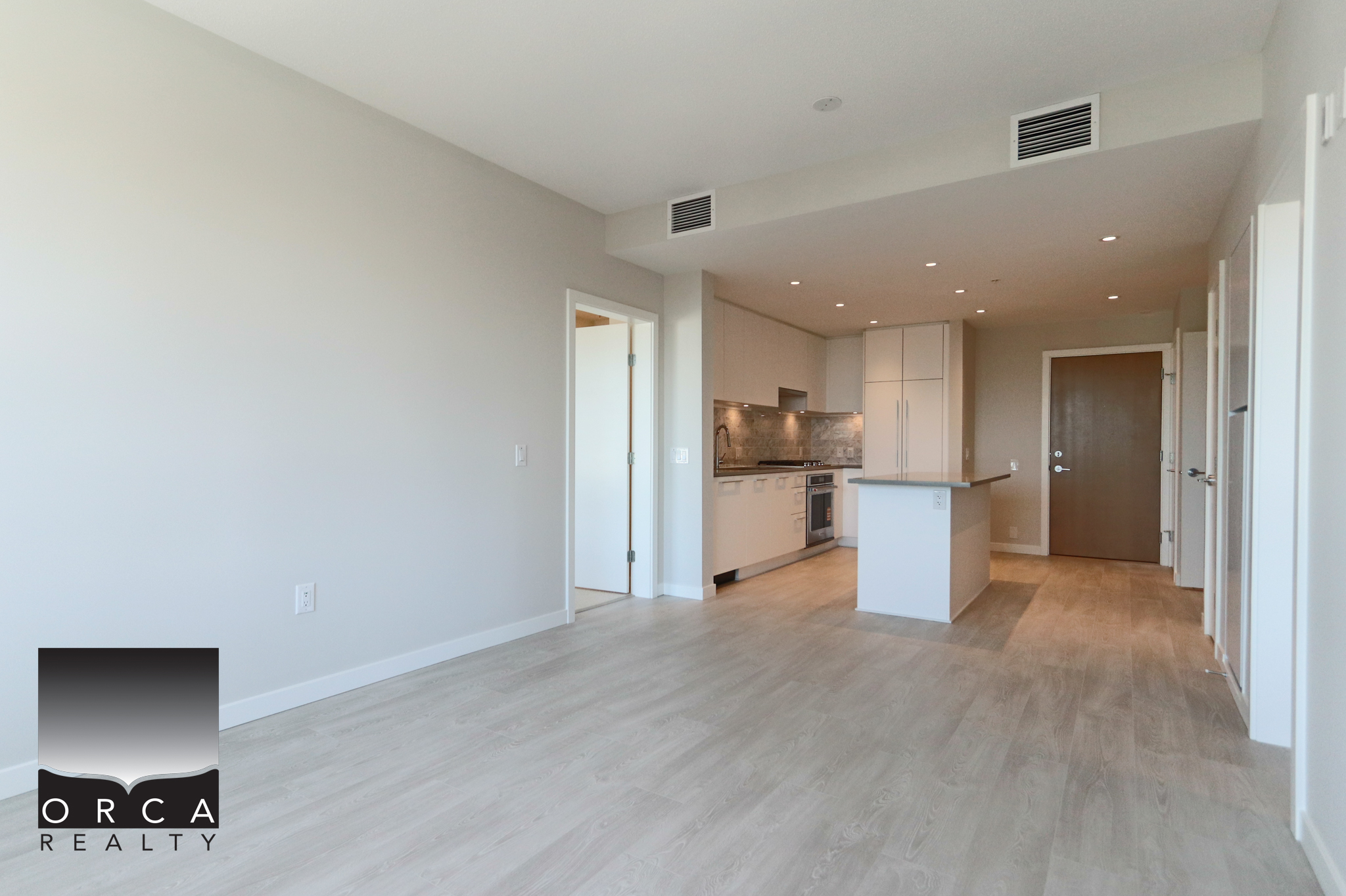 Modern open-concept kitchen and living space Bright, modern open-concept kitchen and living area with white cabinetry, stainless steel appliances, and light wood flooring, ideal for contemporary Vancouver Island homes.