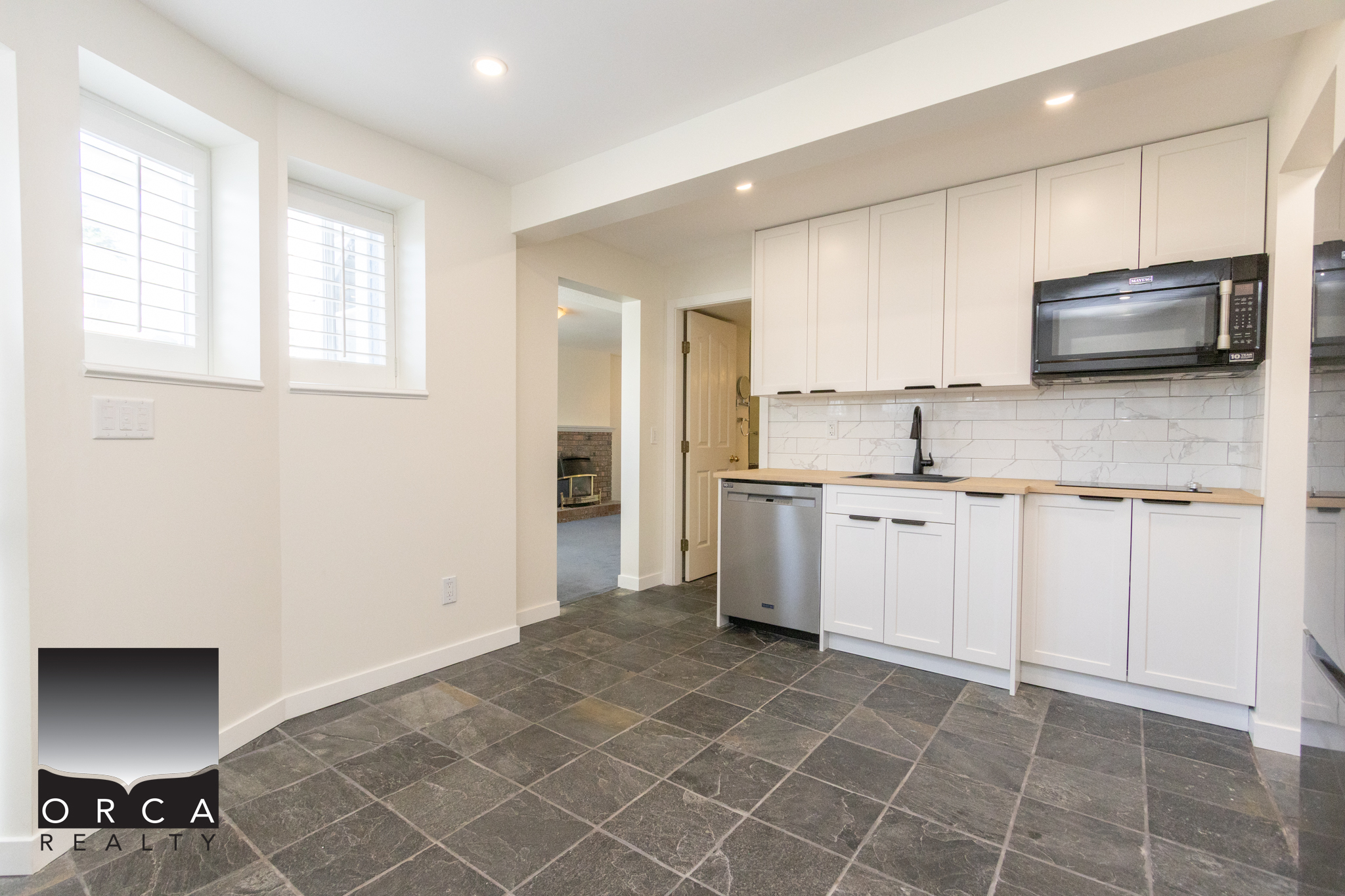 Modern kitchen with white cabinetry, black countertops, and stainless steel appliances in a bright, open-concept home. Perfect for contemporary living and entertaining.