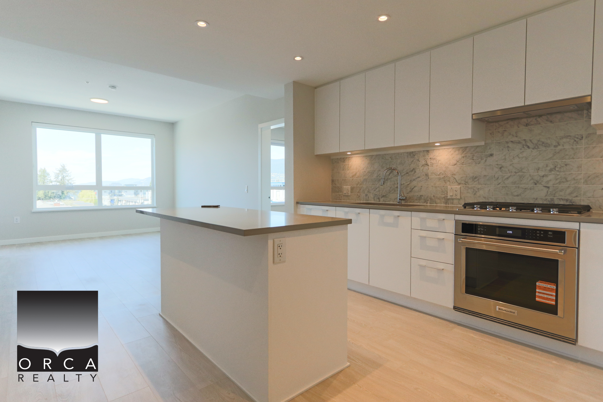 Modern kitchen with white cabinets and marble backsplash Bright, modern kitchen featuring white cabinetry, marble backsplash, and stainless steel appliances in a spacious open-concept living area.