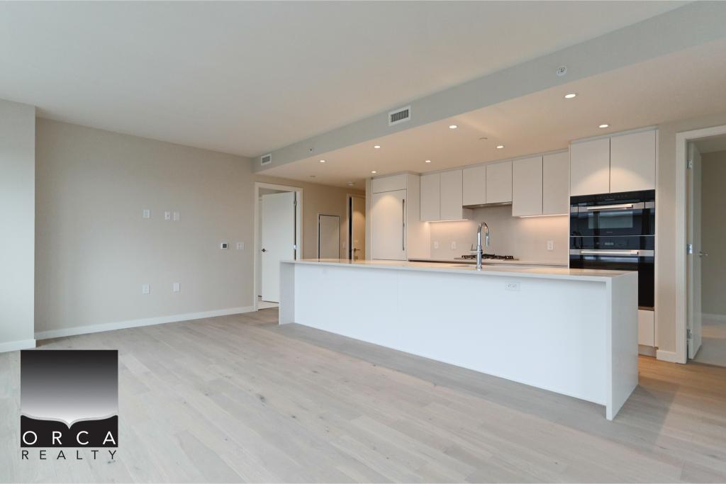 Bright, spacious kitchen featuring contemporary white cabinets, stainless steel appliances, and a large island, ideal for modern Vancouver Island homes and real estate listings.