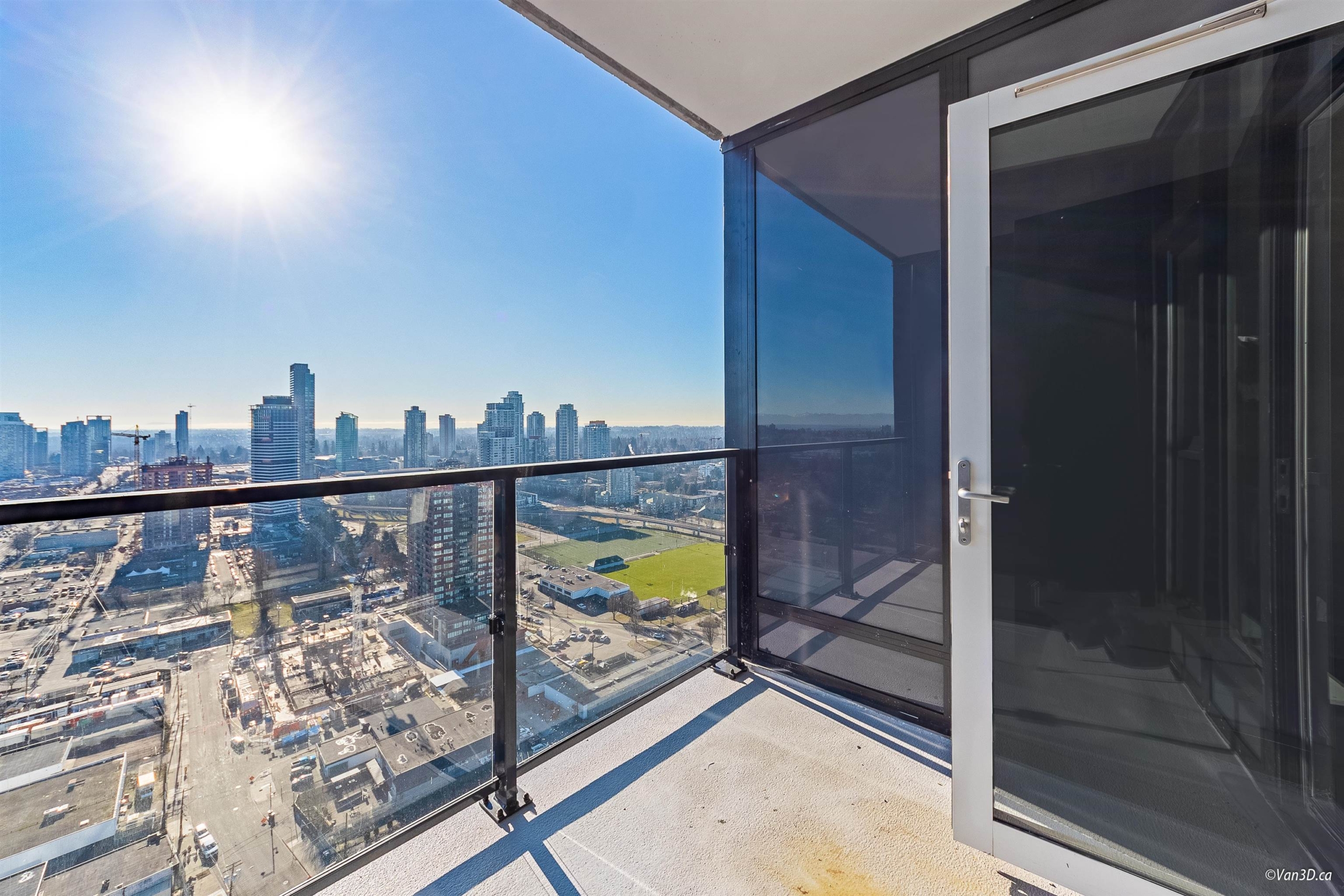Bright and spacious balcony overlooking Vancouver's downtown skyline with glass railing and clear glass doors.