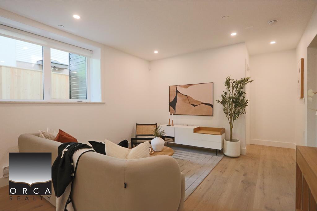 Spacious living room featuring minimalist decor, a comfortable beige sofa, modern artwork, and a large window allowing natural light to brighten the space. Perfect for showcasing contemporary home int.