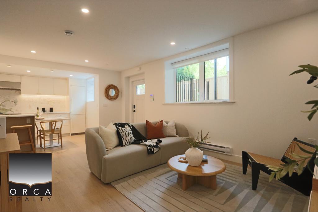 Spacious living room featuring a neutral color palette, large windows allowing ample natural light, a comfortable sofa, and stylish decor, ideal for showcasing a contemporary home in Victoria, BC.