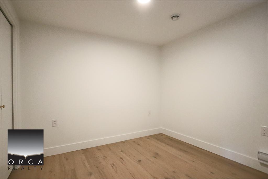 Bright, minimalist empty room with white walls and hardwood flooring, ideal for residential or office space in Vancouver. Perfect for real estate listings showcasing interior features.
