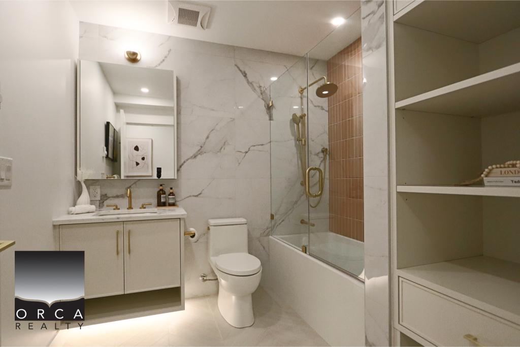 Elegant bathroom featuring marble walls, a glass shower, and contemporary fixtures.