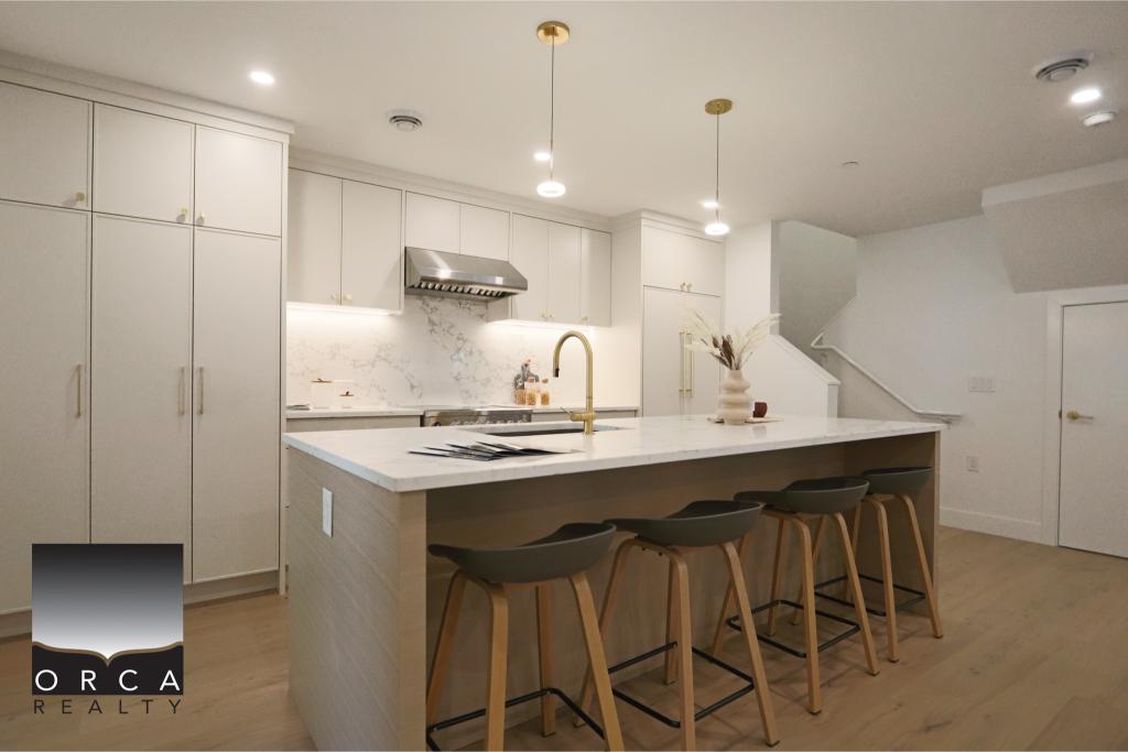 Modern minimalist kitchen featuring sleek white cabinets, a spacious island with seating, and contemporary lighting, ideal for stylish Vancouver-area homes.