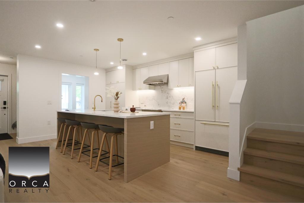 Spacious modern kitchen featuring white cabinetry, a large island with seating, and sleek appliances, perfect for contemporary home living.