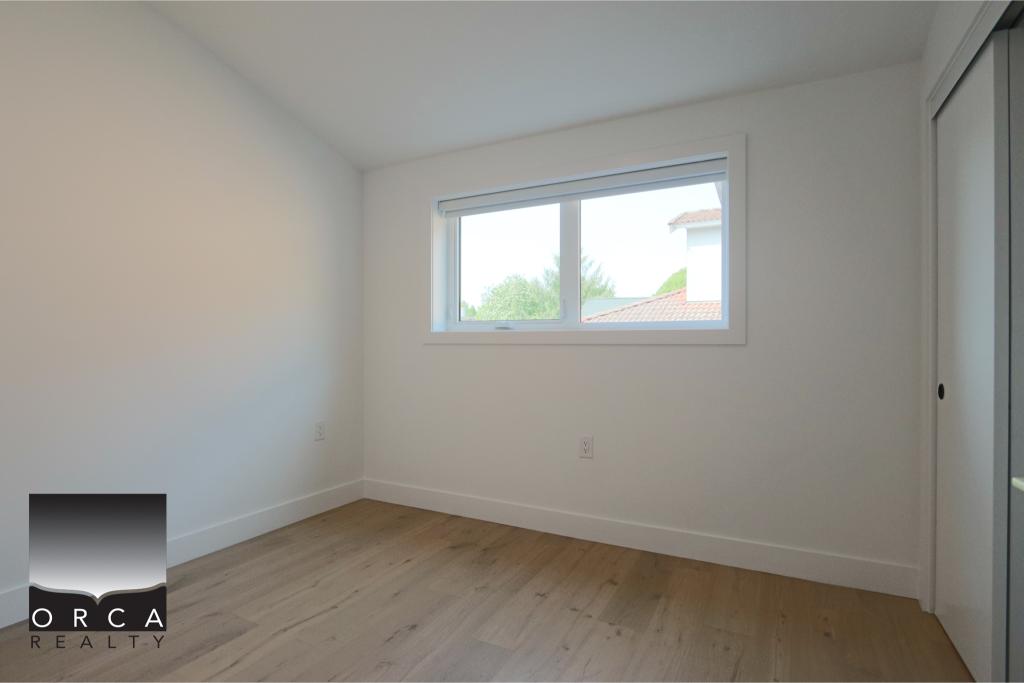 Bright, spacious bedroom with large window, white walls, and built-in closet, ideal for homebuyers or renters seeking a clean, minimalist space in a Vancouver area property.