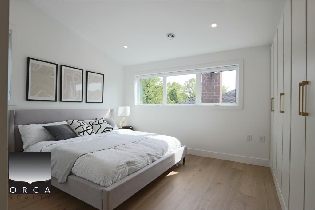 Bright and airy bedroom featuring minimalist decor and large window with views of greenery. Perfect for relaxing and restful sleep.
