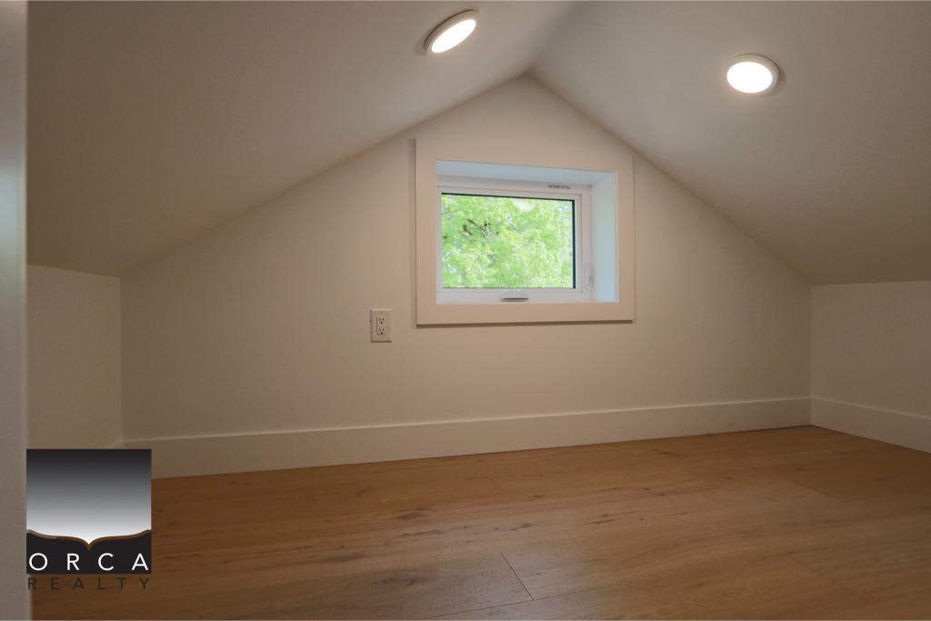 Attic room featuring a small window, sloped ceiling, and recessed lighting, ideal for a cozy home office or storage space.