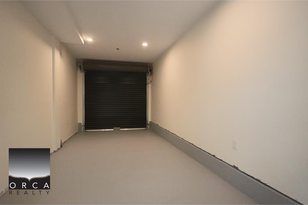 Empty commercial garage with roller shutter door, clean concrete floor, and white walls, ideal for storage or business use in Vancouver.