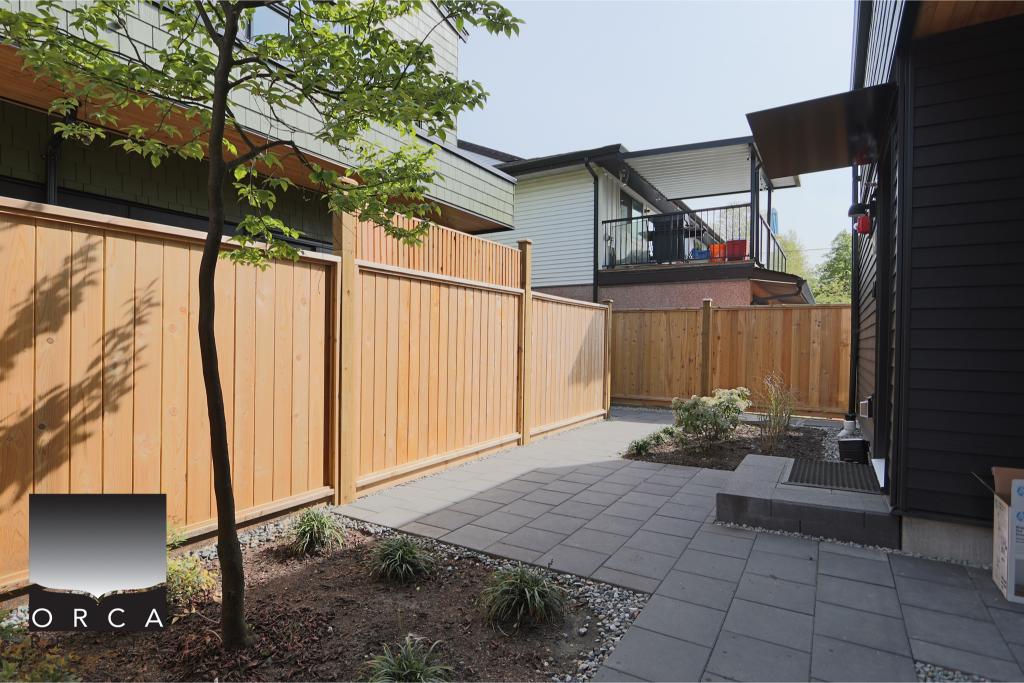 Spacious backyard featuring a new wooden privacy fence and a paved patio area, perfect for outdoor living and entertaining in Vancouver.