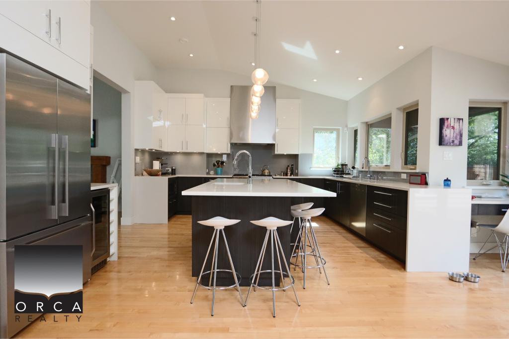 Spacious contemporary kitchen featuring stainless steel appliances, a central island with seating, and ample natural light, ideal for modern home living and entertaining.