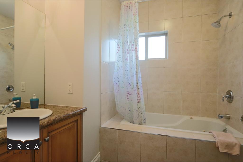 Bright bathroom featuring a bathtub with a showerhead, a small window, and a colorful shower curtain, ideal for relaxing baths and convenient showering.