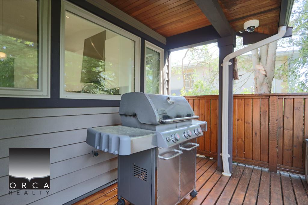 Outdoor BBQ grill on a wooden deck with privacy fencing, perfect for outdoor cooking and entertaining in a cozy residential setting.