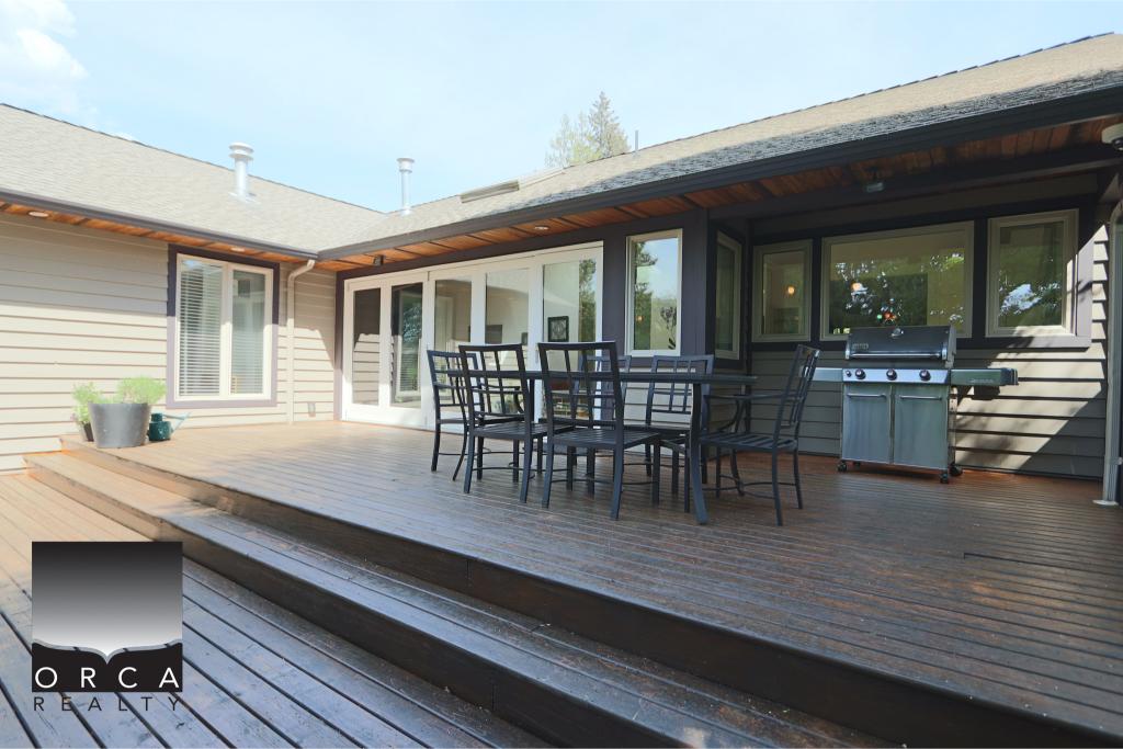 Outdoor deck with patio furniture and BBQ grill in a residential backyard.