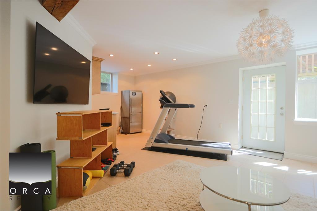 Bright home gym with treadmill, free weights, and storage shelves in a modern, well-lit basement. Perfect for fitness enthusiasts seeking a private workout space.